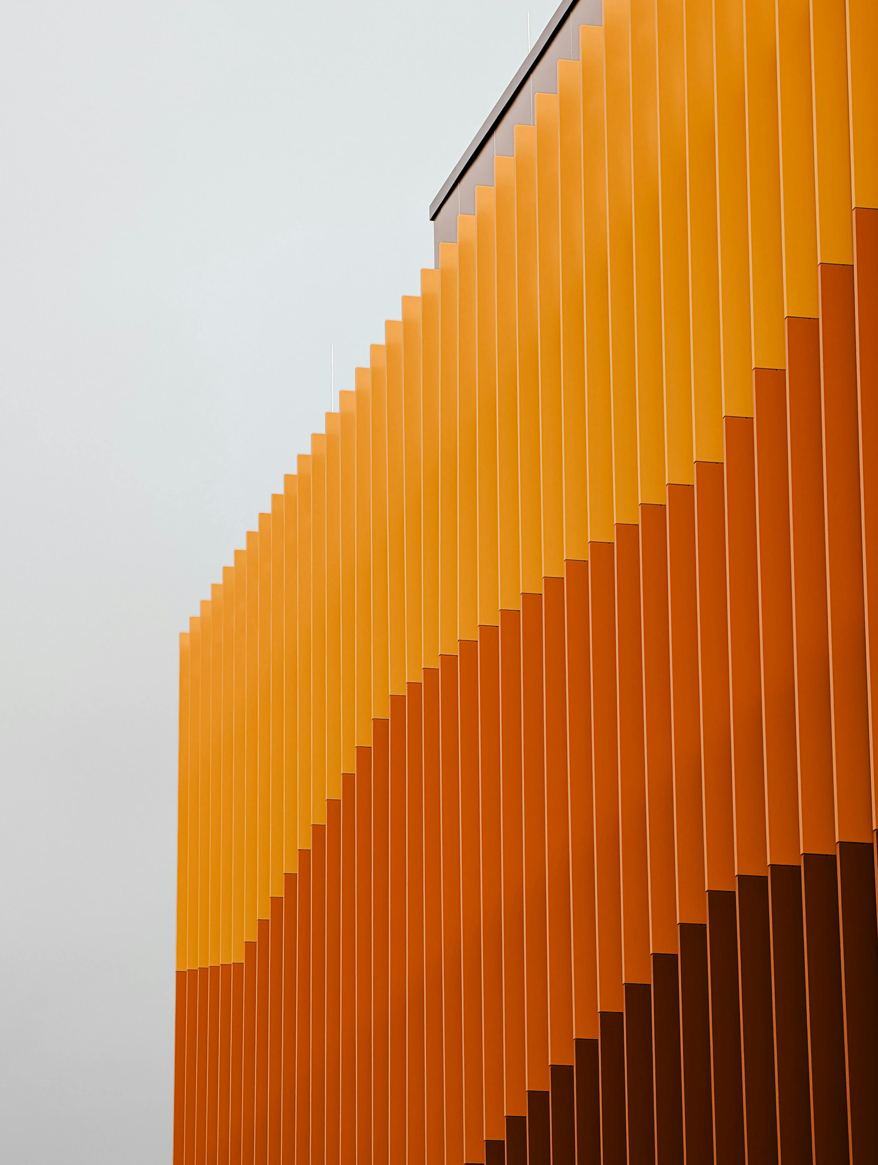 Abstract view of orange building facade with vertical lines. Captures modern architectural elegance.