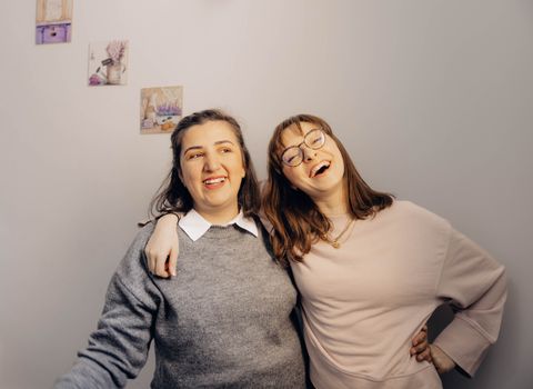 Warm and joyful moment of two friends laughing and embracing indoors.