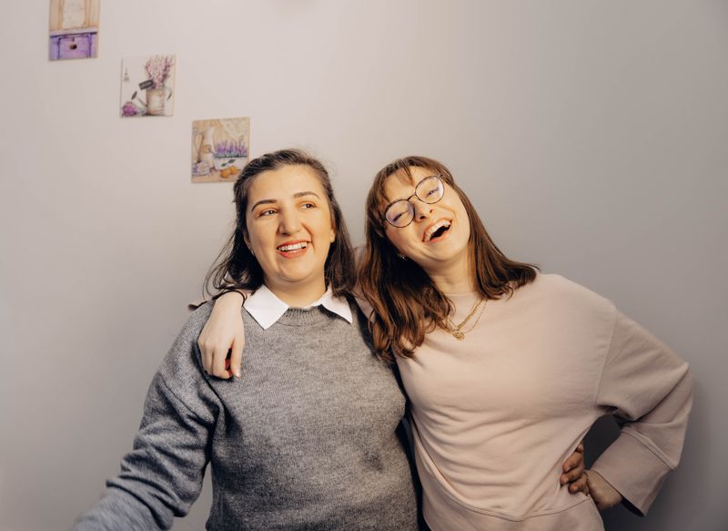 Warm and joyful moment of two friends laughing and embracing indoors.