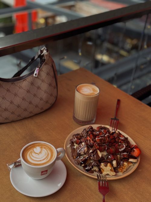 Free Delicious cappuccino and waffles topped with chocolate in a café setting. Stock Photo