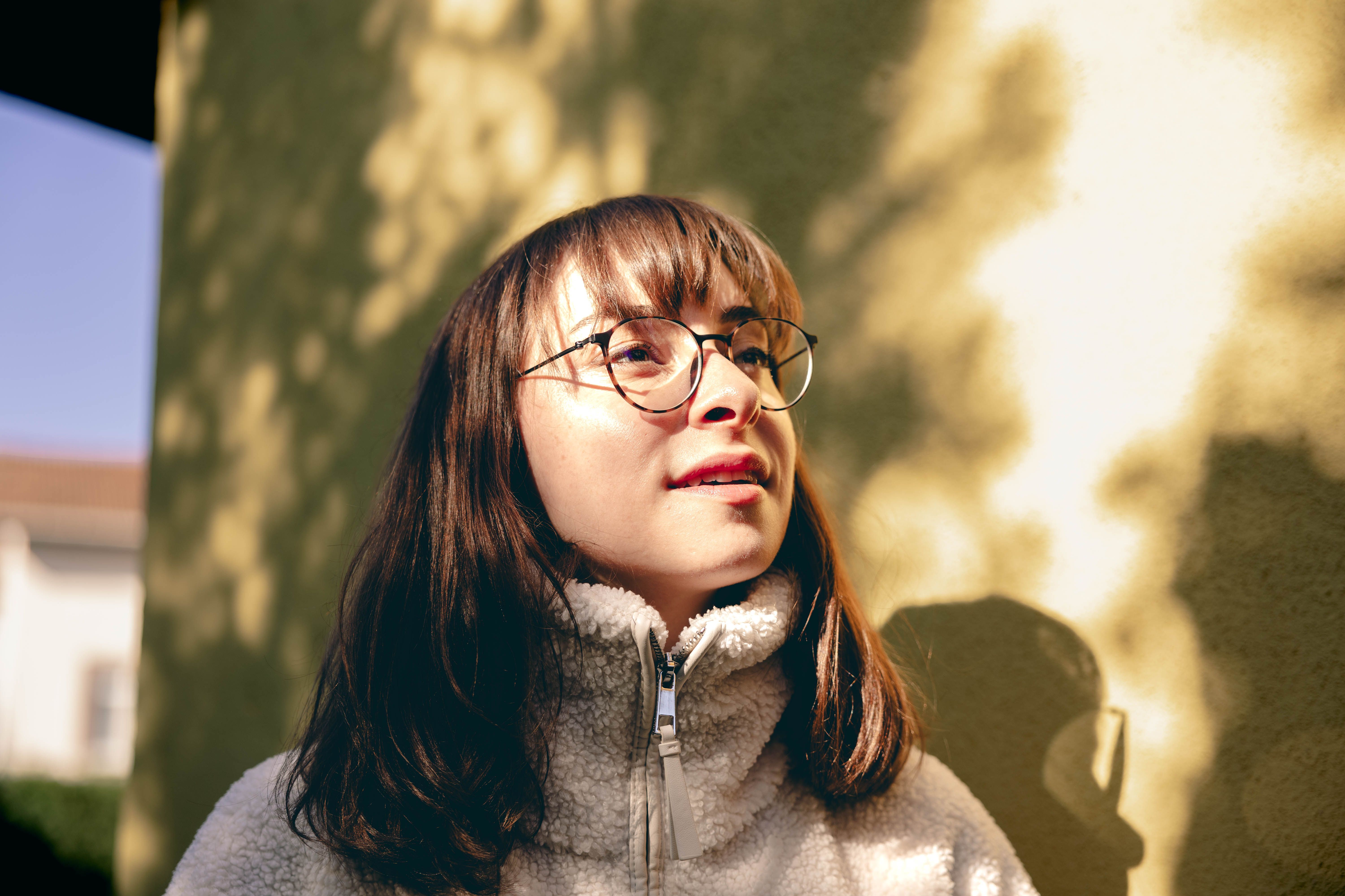 A woman with glasses in a warm outdoor setting, enjoying the sunlight. Perfect for lifestyle and fashion concepts.