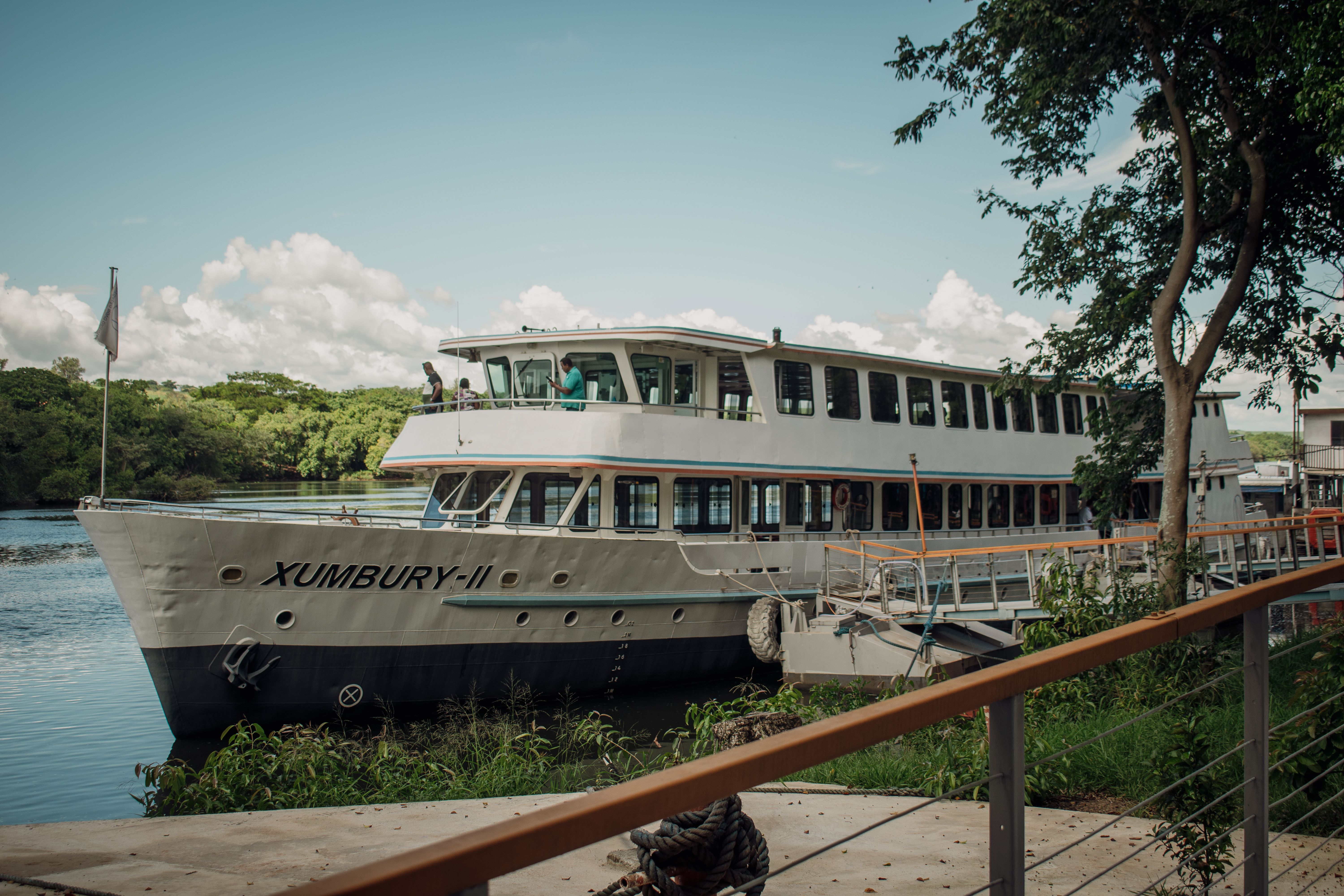 A riverboat named Xumbury-II docked by lush greenery, perfect for travel imagery.