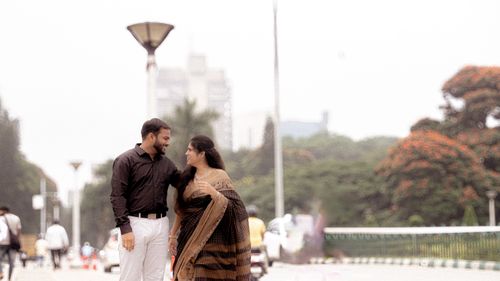 Free A smiling couple walks arm in arm in an urban park during the day. Stock Photo