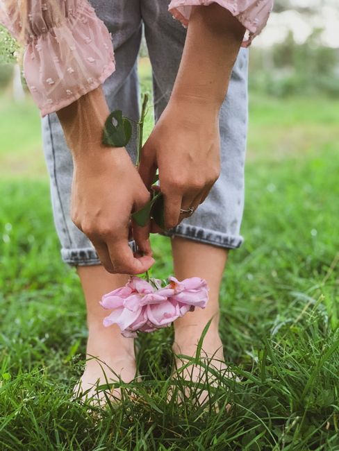 Close-up of hands holding a pink rose against a green grass background, reflecting calm nature.