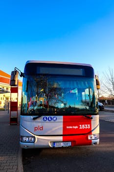 Front view of a public bus parked in Líbeznice, Czech Republic, on a clear sunny day.