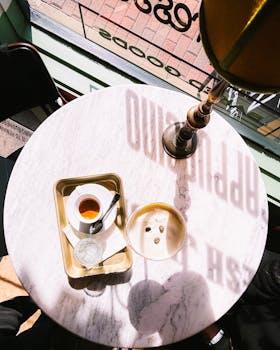 Flat lay of coffee on a marble table with afternoon sunlight casting shadows.