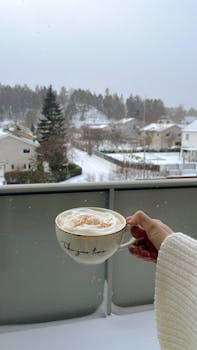 Enjoying a warm coffee on a snowy winter day in Stockholm, overlooking a serene residential neighborhood.