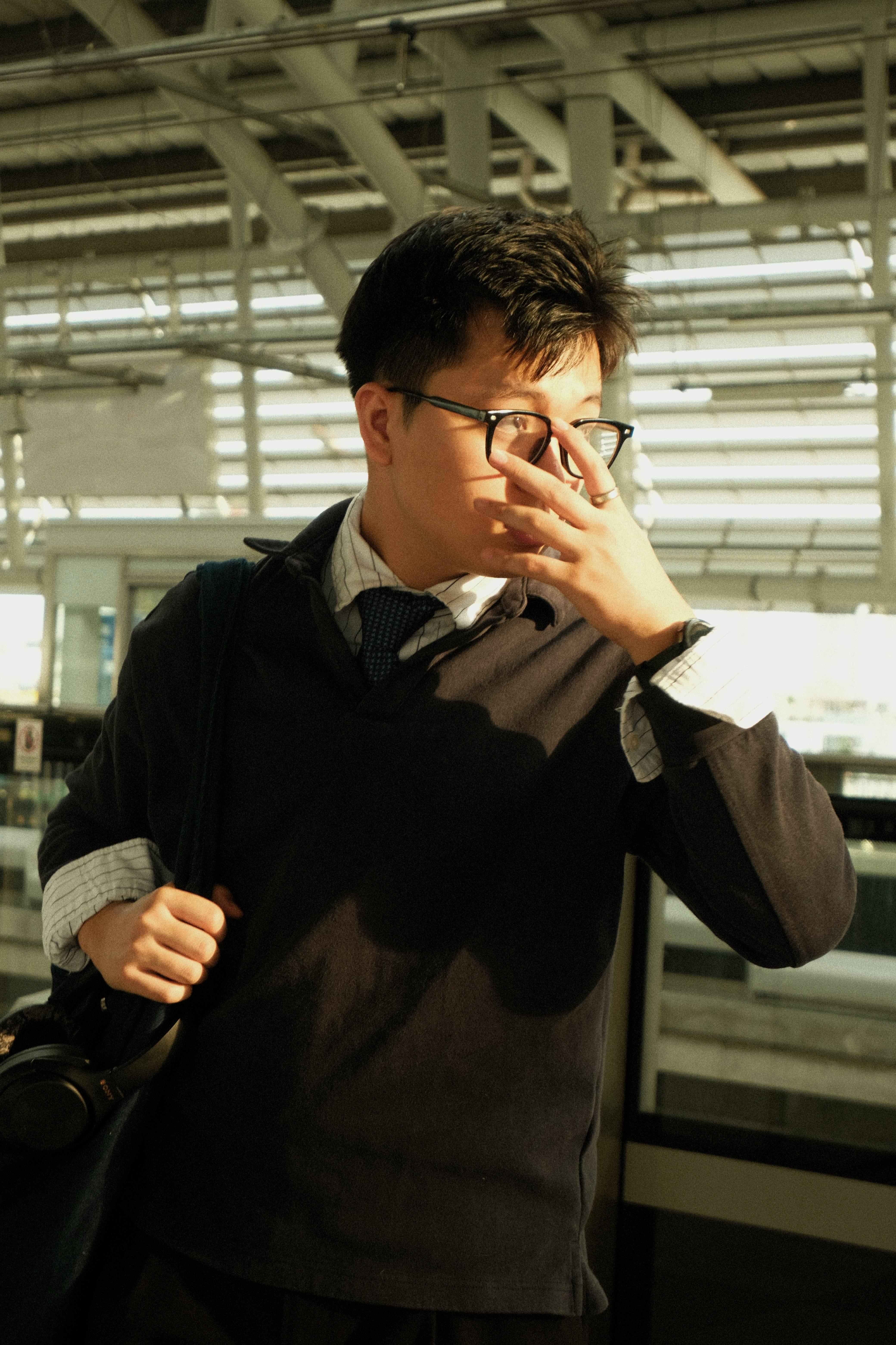 grátis Jovem profissional em trajes profissionais em uma estação de trânsito contemporânea, ajustando óculos. Foto profissional