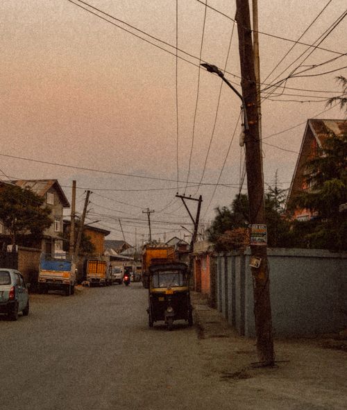 Free Scene of a quiet urban street at dusk, featuring a tuk-tuk and overhead wires. Stock Photo