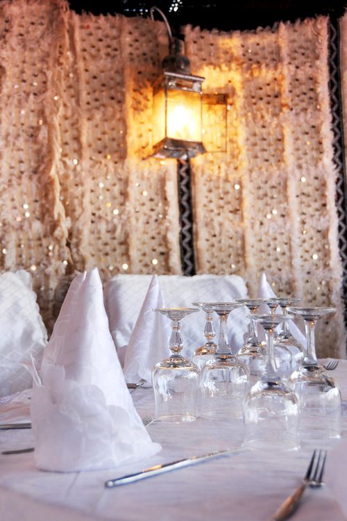 Free A sophisticated table setting with folded napkins and glasses, lit by a warm lantern. Stock Photo