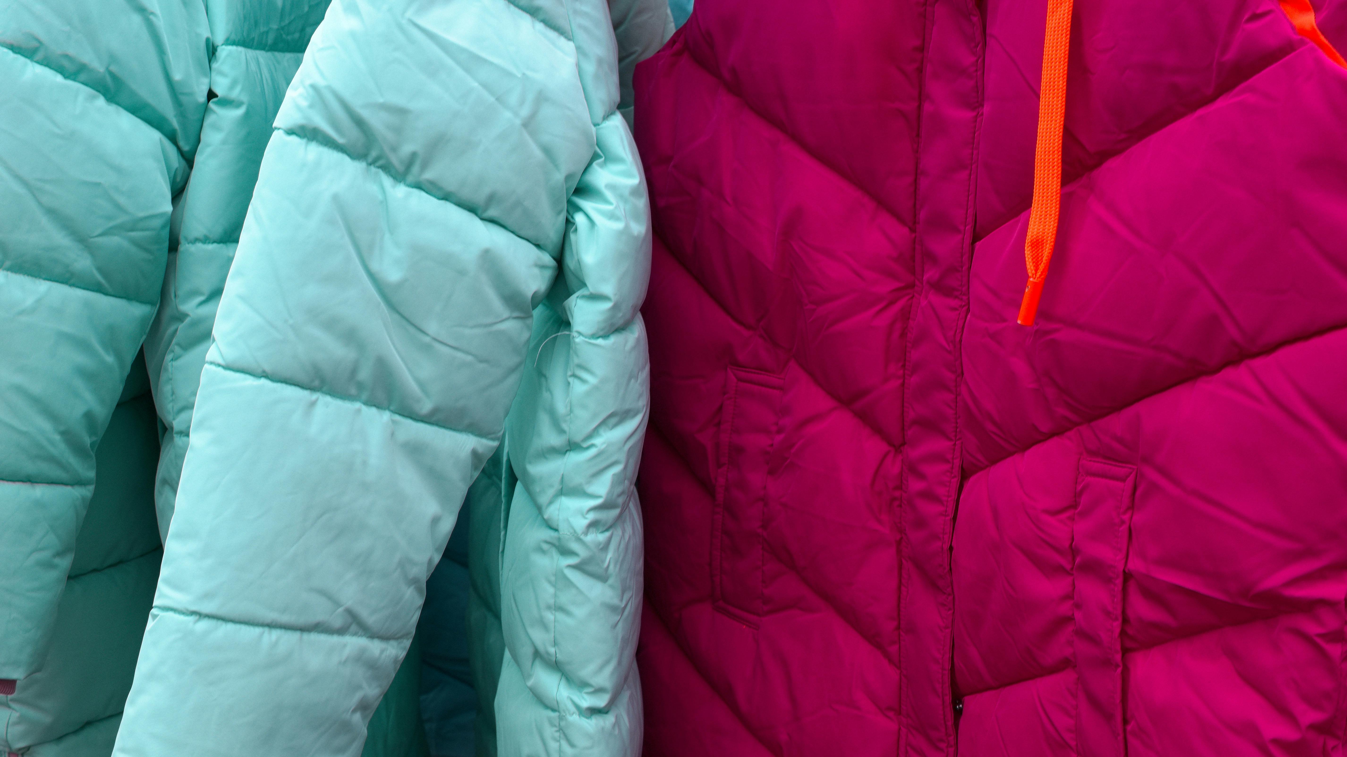 Close-up of vibrant turquoise and magenta puffer jackets, ideal for winter fashion.
