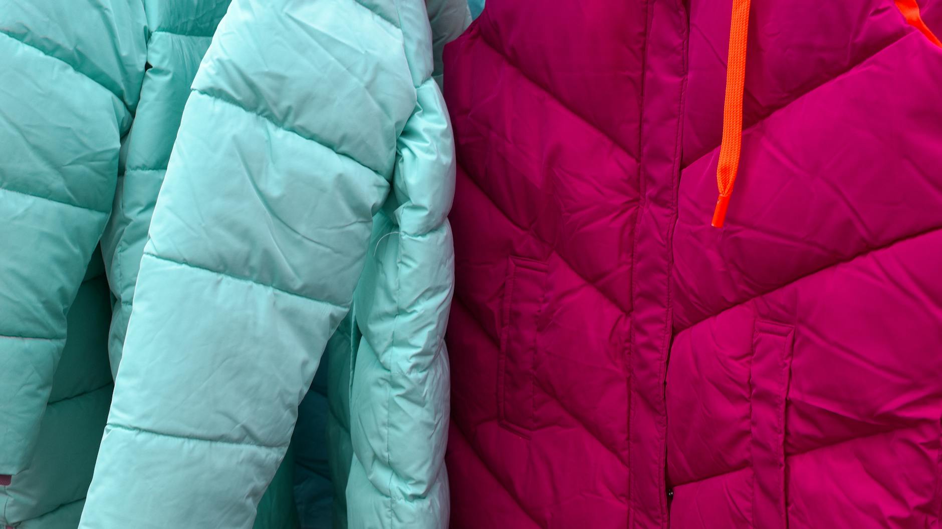 Close-up of vibrant turquoise and magenta puffer jackets, ideal for winter fashion.