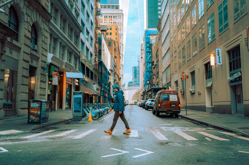 A person crosses a street in downtown Manhattan, New York during winter.