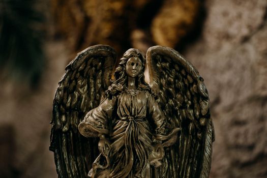 Intricate bronze angel statue with detailed wings in a soft-focus background.