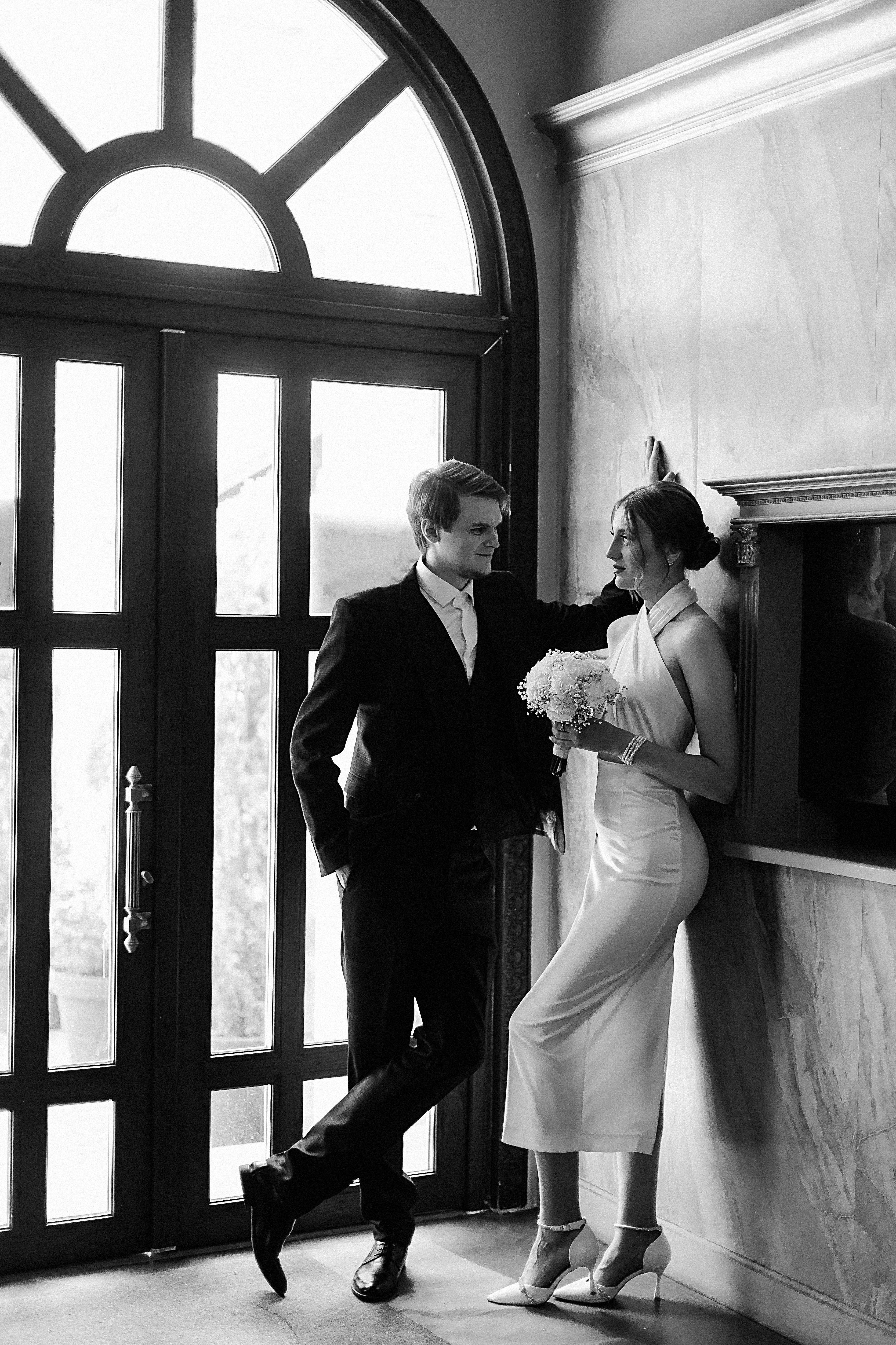 A stylish black and white portrait of a bride and groom in a classic wedding pose.
