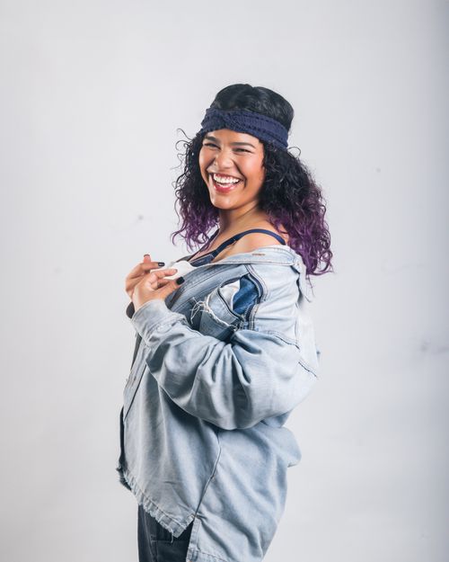 Free Cheerful woman in denim jacket poses confidently with a vibrant smile indoors. Stock Photo