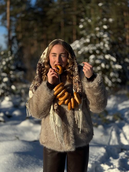 Free Smiling woman in fur coat eating sausages on a snowy winter day outdoors. Stock Photo