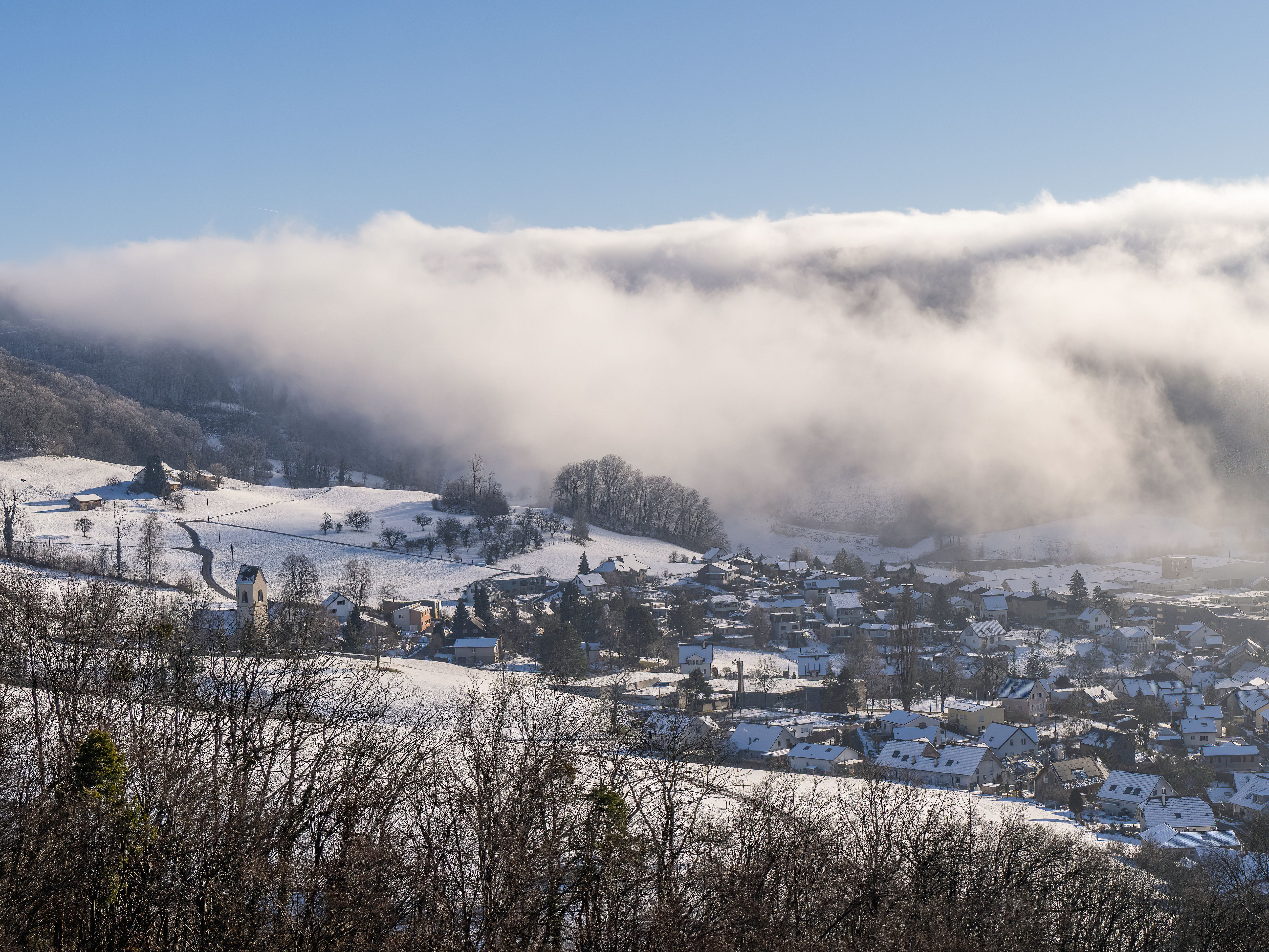 A snow-covered town on a hillside under a low bank of cloud