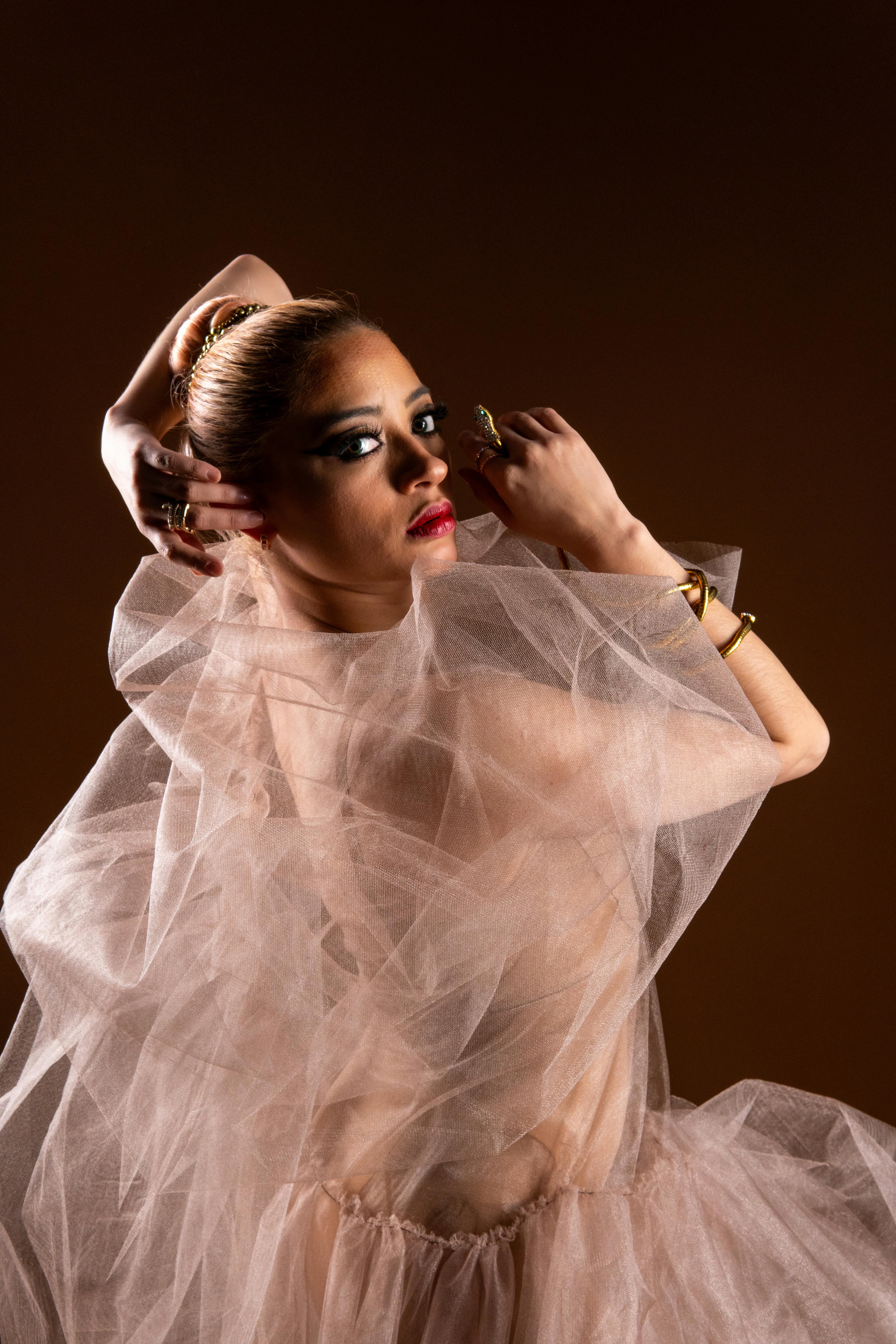 Free A young ballerina in a dramatic pose showcasing elegance with a mocha backdrop. Stock Photo