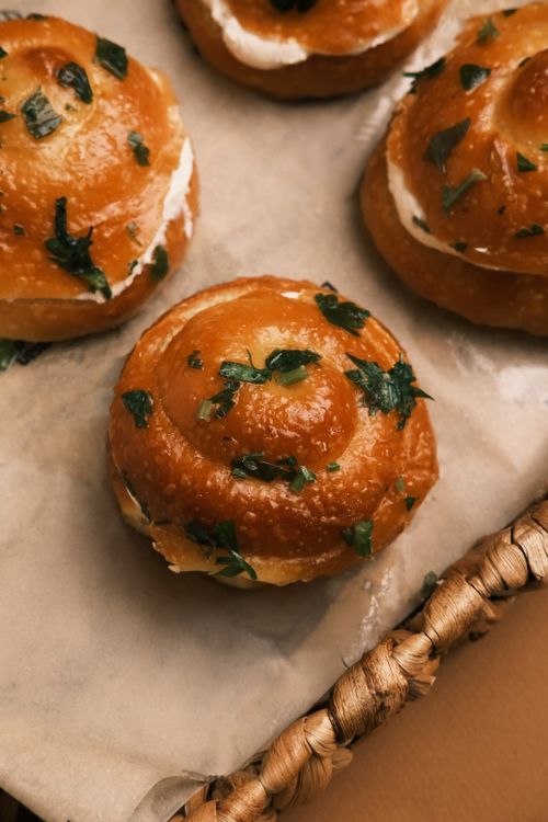 Free Gourmet artisan pastries topped with fresh herbs, showcasing rustic charm in a cozy bakery setting. Stock Photo