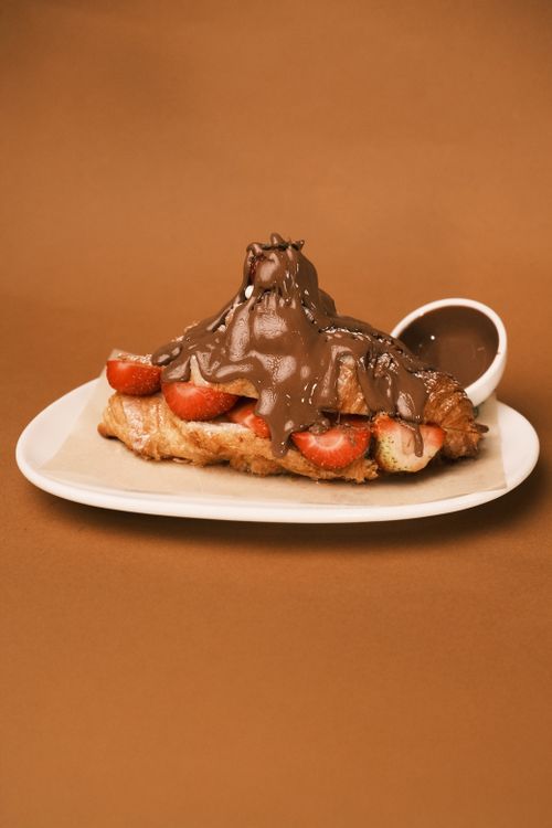 Free Delicious croissant topped with chocolate sauce and fresh strawberries on a plate. Stock Photo