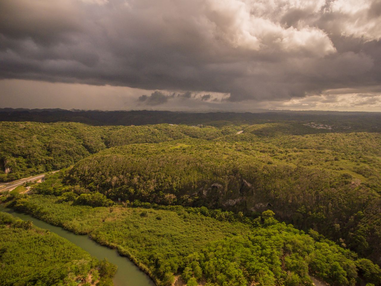 aerial view of lush green landscape under a dramatic cloudy sky featur