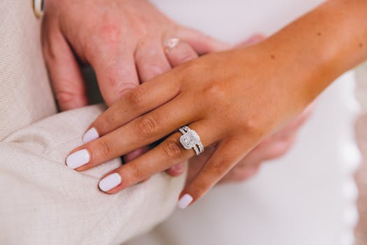 A close-up of a couple holding hands, showcasing a stunning diamond wedding ring.