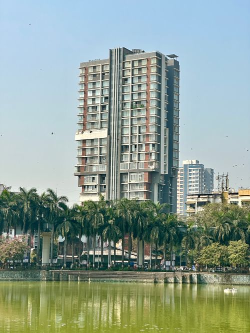 Free A tall residential building overlooking a lake with palm trees in Mumbai, India. Stock Photo