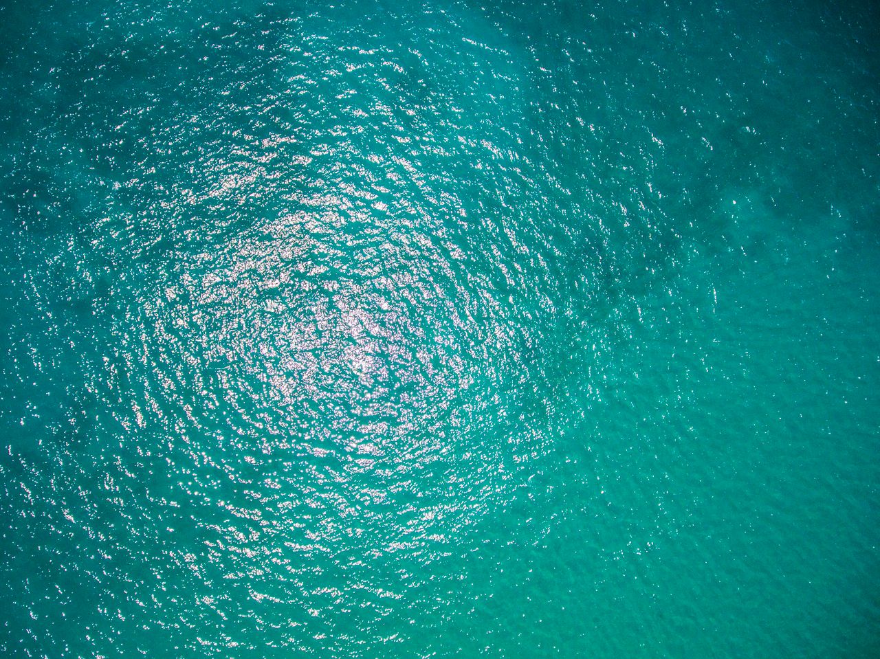 a high angle aerial shot showcasing shimmering turquoise ocean waves u
