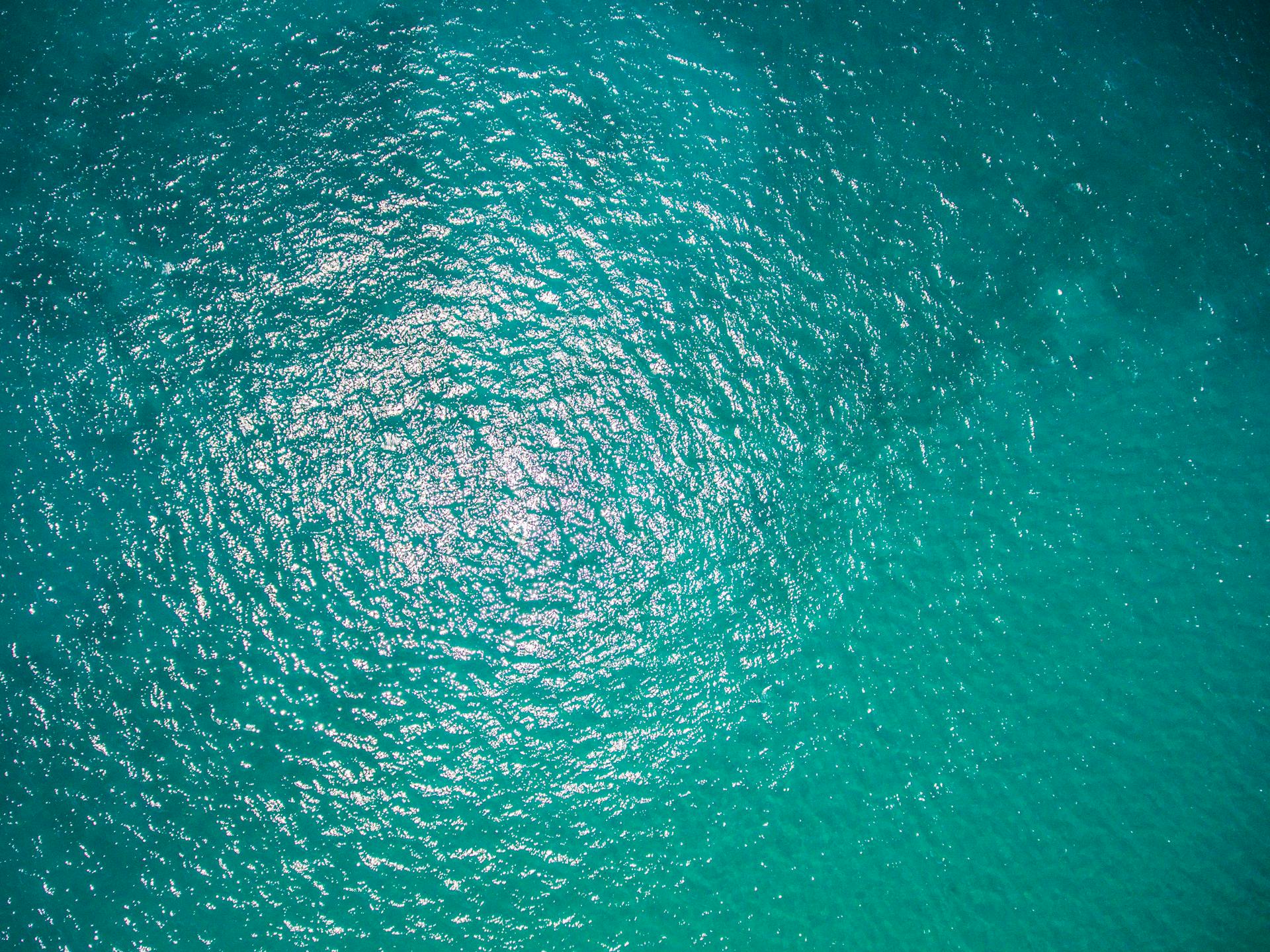 A high-angle aerial shot showcasing shimmering turquoise ocean waves under sunlight.