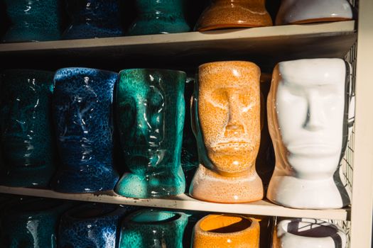A vibrant display of ceramic pottery heads in various colors on a shelf.