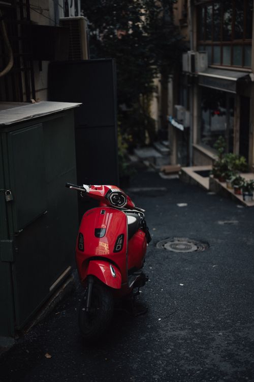 Free A vibrant red scooter parked in a moody, narrow alley in Istanbul's Beyoğlu district. Stock Photo