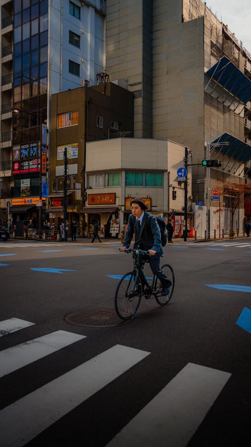 Free A cyclist rides through a busy intersection in Kamakura, Japan, showcasing urban life. Stock Photo