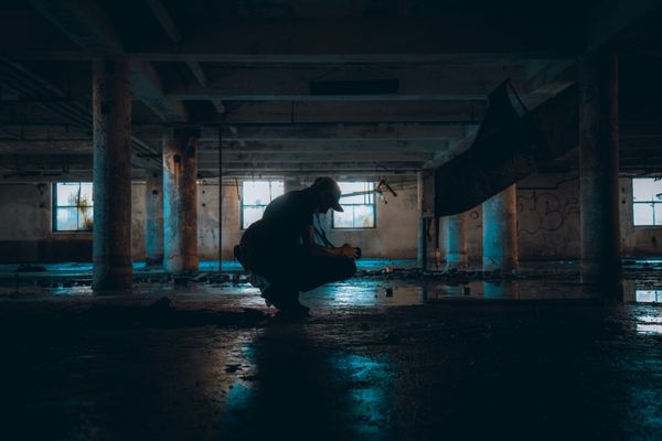 A crouching silhouette inside an abandoned warehouse — photo by Mike Norris on Pexels