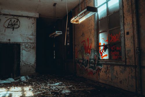 Free Rustic abandoned room with graffiti, broken windows, and hanging lights. Stock Photo