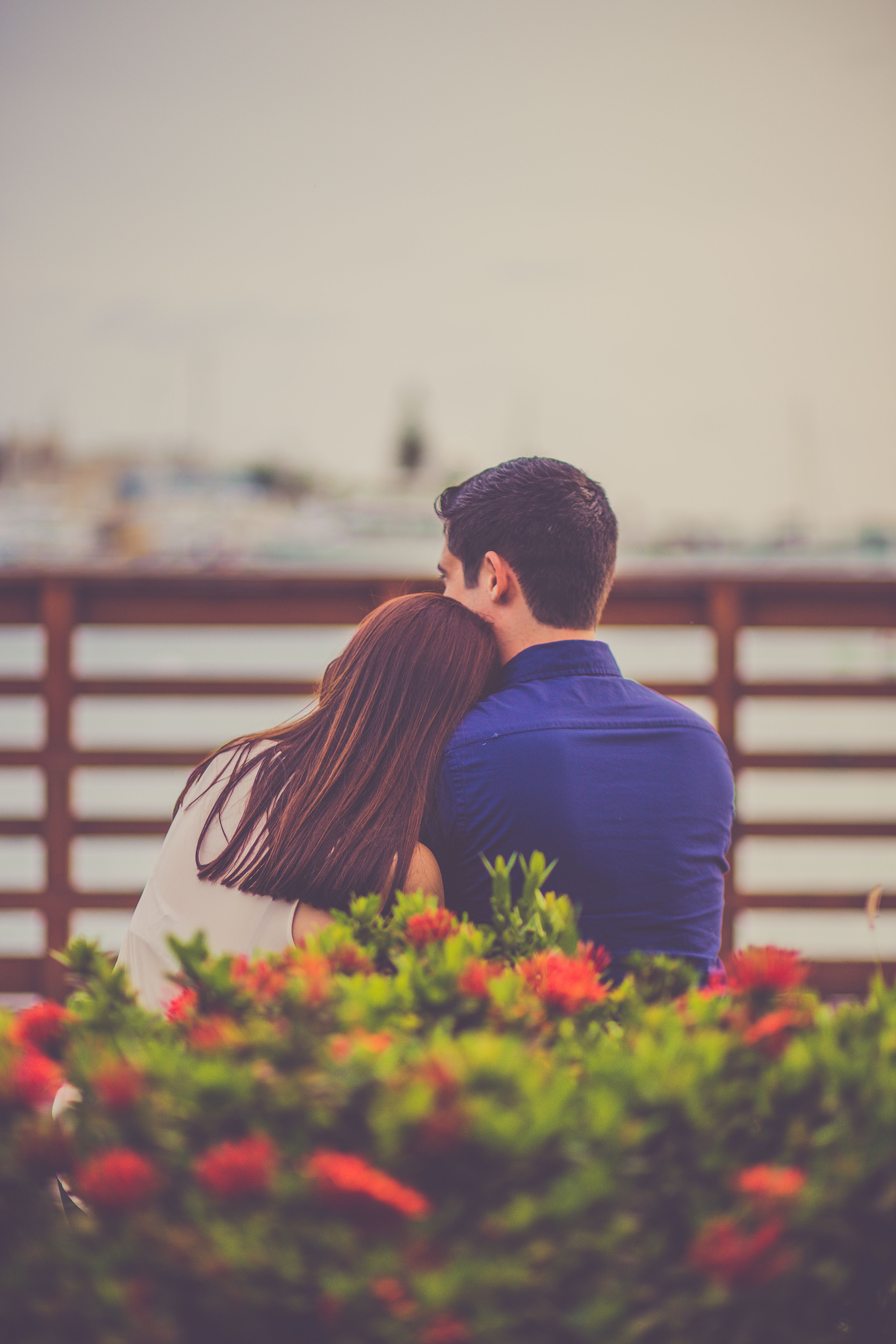 A couple enjoying a romantic moment by the lakeside, surrounded by vibrant flowers.