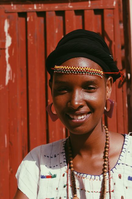 Portrait of a smiling woman in traditional outfit with accessories and beads.