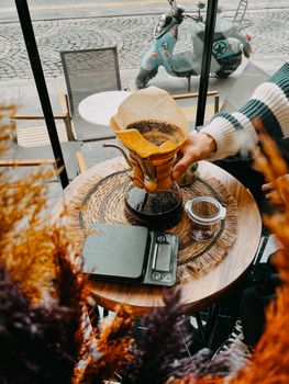 Warm cafe scene featuring a pour-over coffee maker on a wooden table.