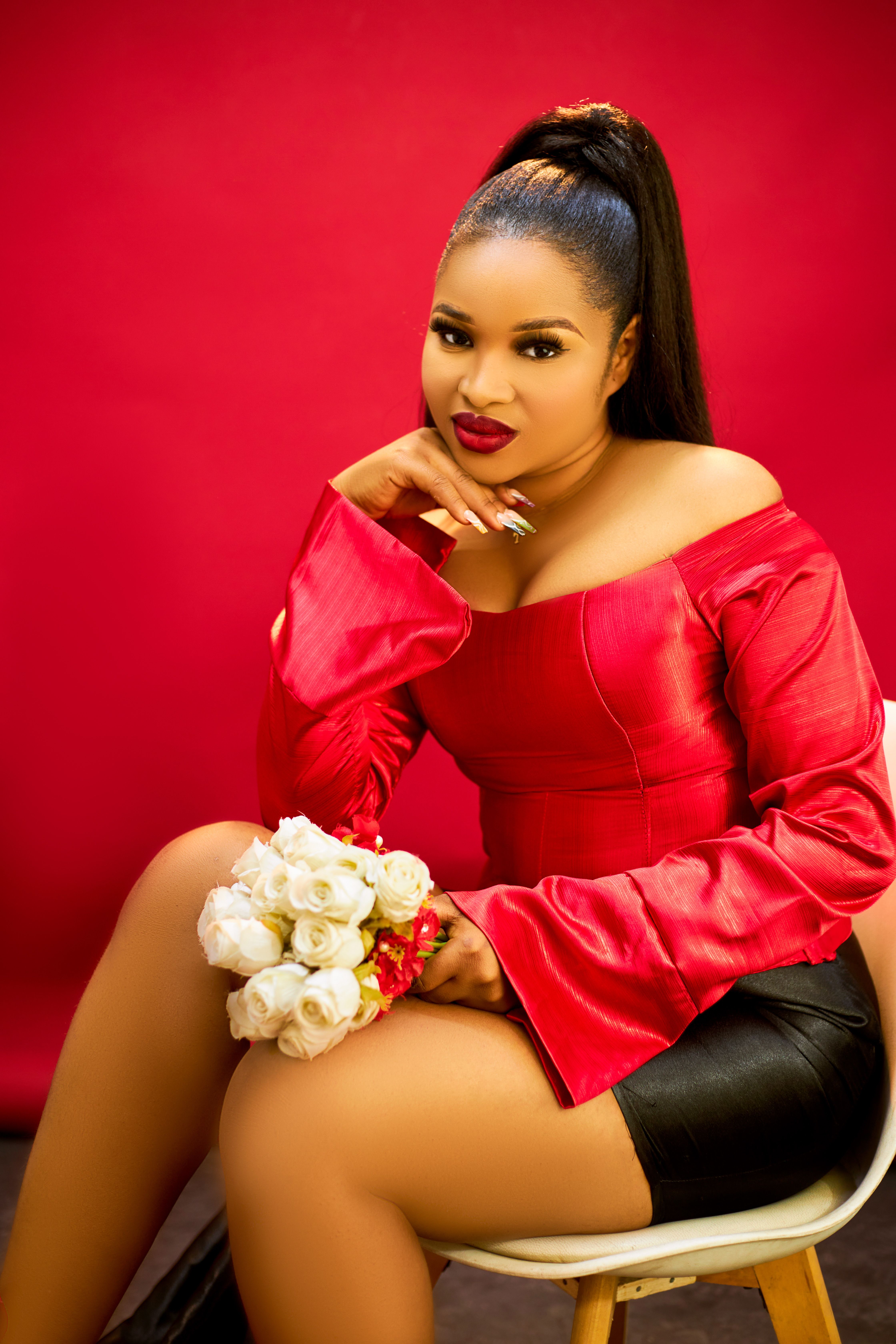 Beautiful woman in stylish red dress holding white roses against a vibrant backdrop.