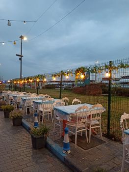 Charming outdoor restaurant seating with decorative string lights under an evening sky.