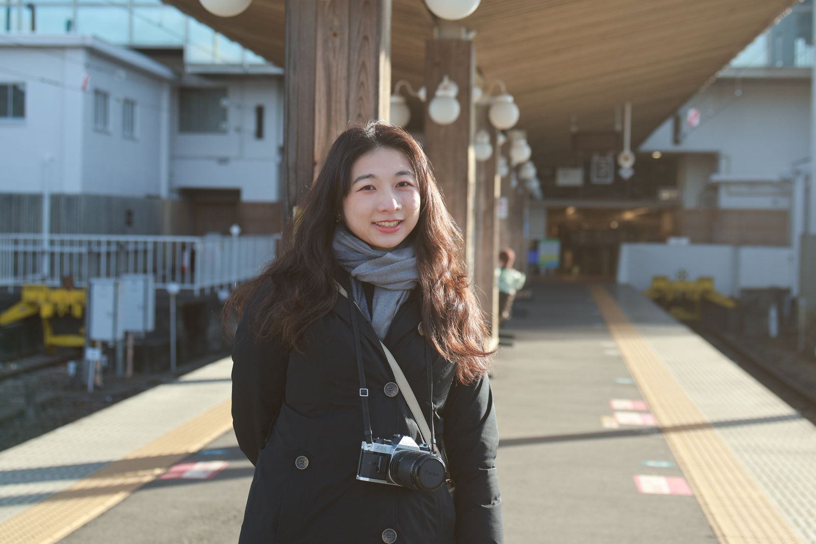 Jeune femme souriante dans une gare baign&eacute;e de lumi&egrave;re