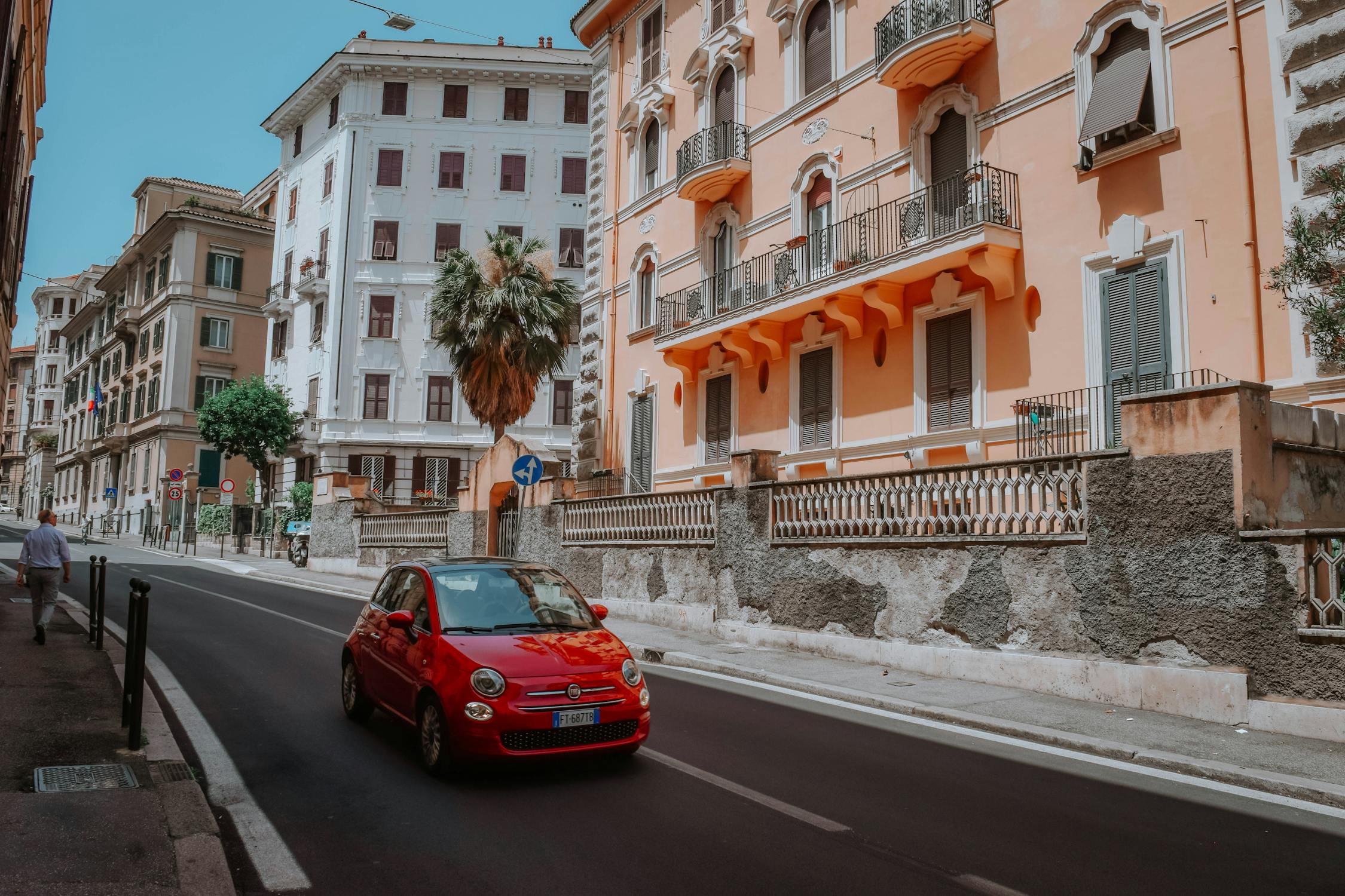 A red car passing by a street in Rome