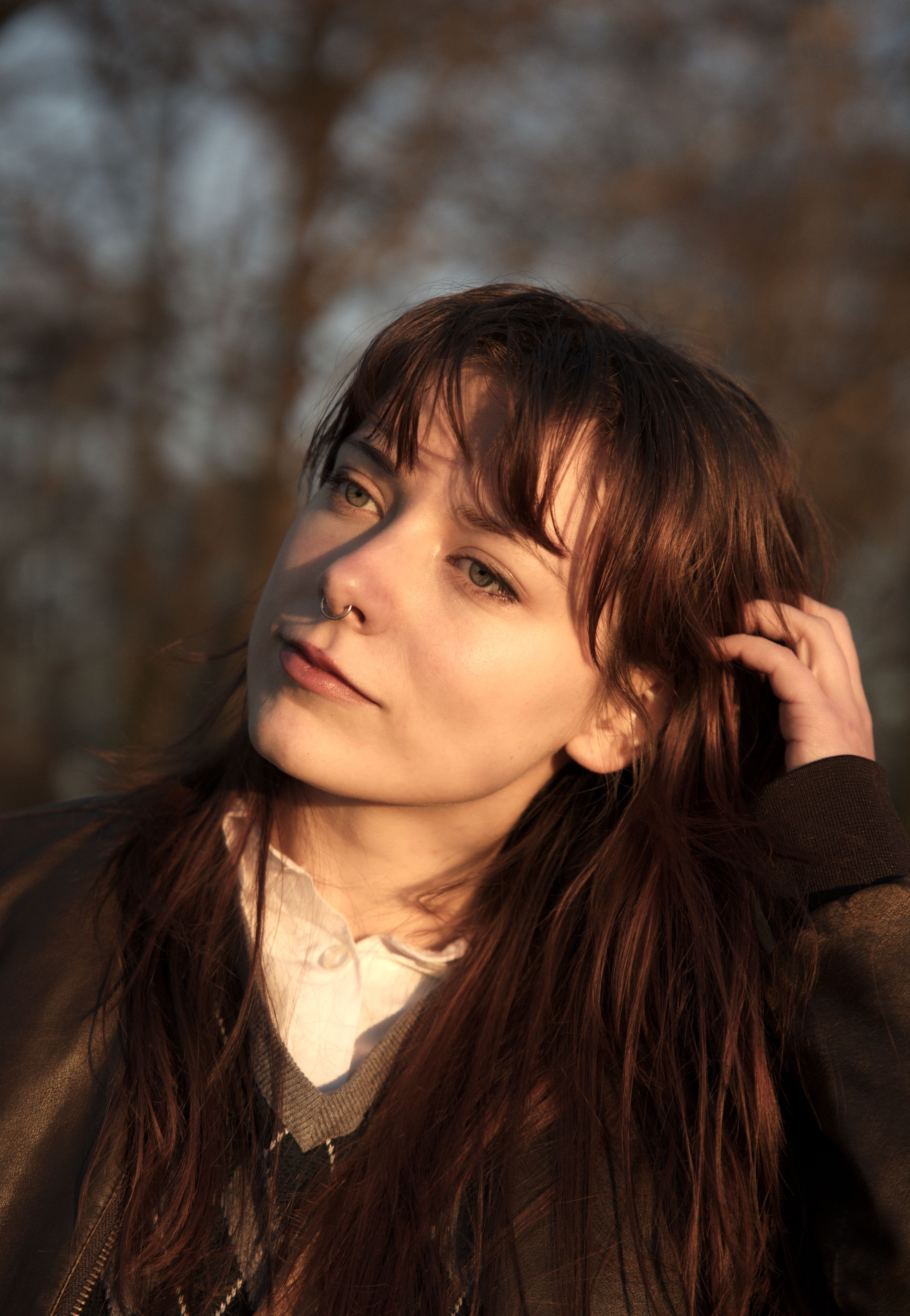 Elegant portrait of a young woman enjoying autumn sunlight in nature.