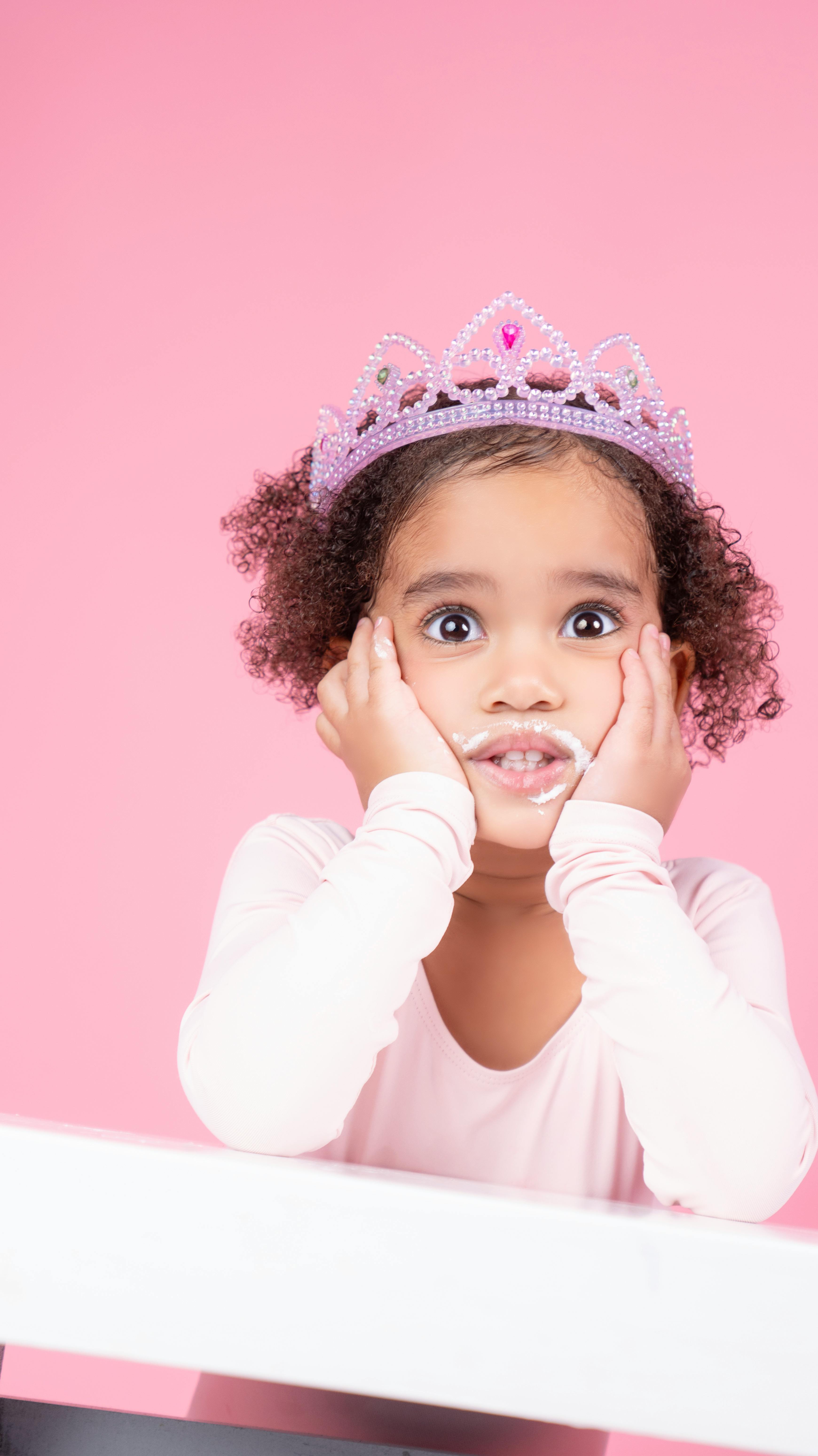 Young girl in pink princess attire with whimsical expression