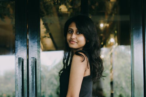 Free A young woman with long hair standing indoors, creating a serene and modern atmosphere. Stock Photo