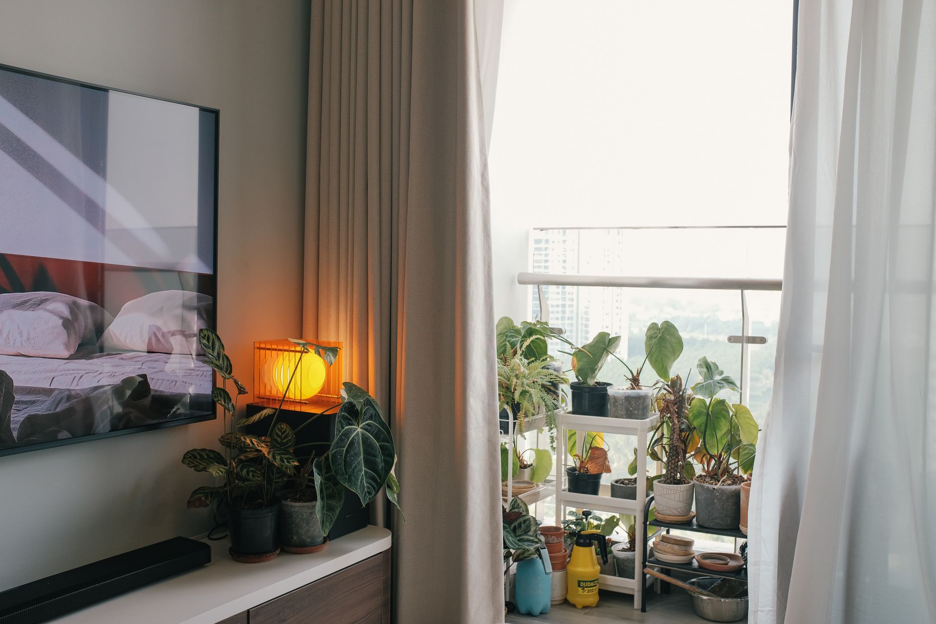 warm apartment decor with DIY hacks Warm indoor space featuring cozy decor and lush balcony plants in soft lighting.