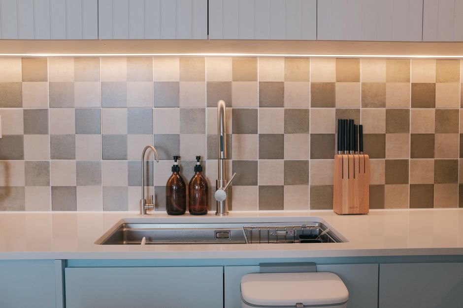 Elegant and clean kitchen design featuring a sink with tiled backsplash and knife set.