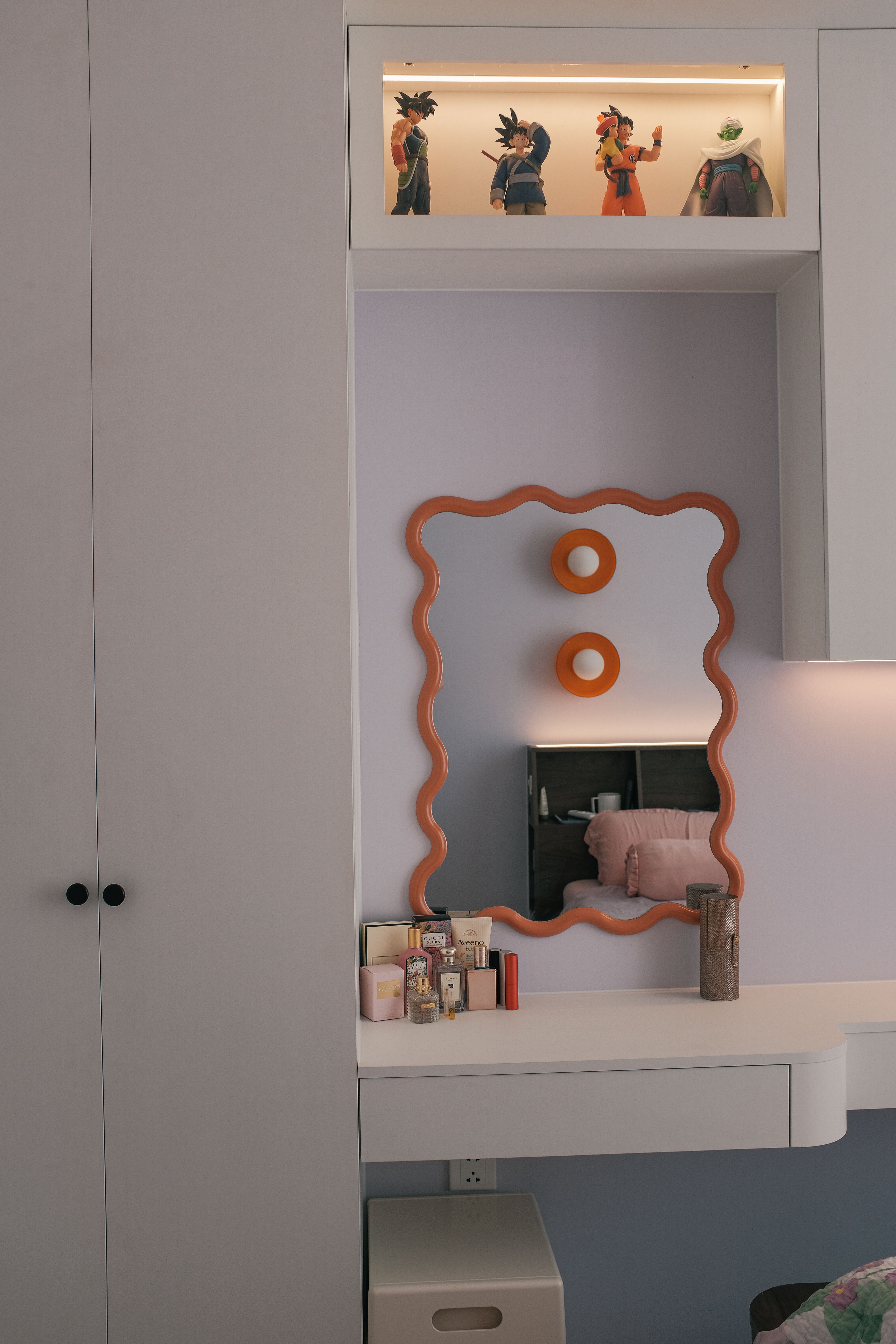 A bedroom with a sculptural mirror and collected objects, the sort of small corner that can make a temporary room feel chosen