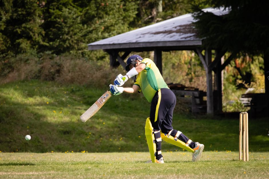 Cricketer hitting the ball during an exciting match outdoors.