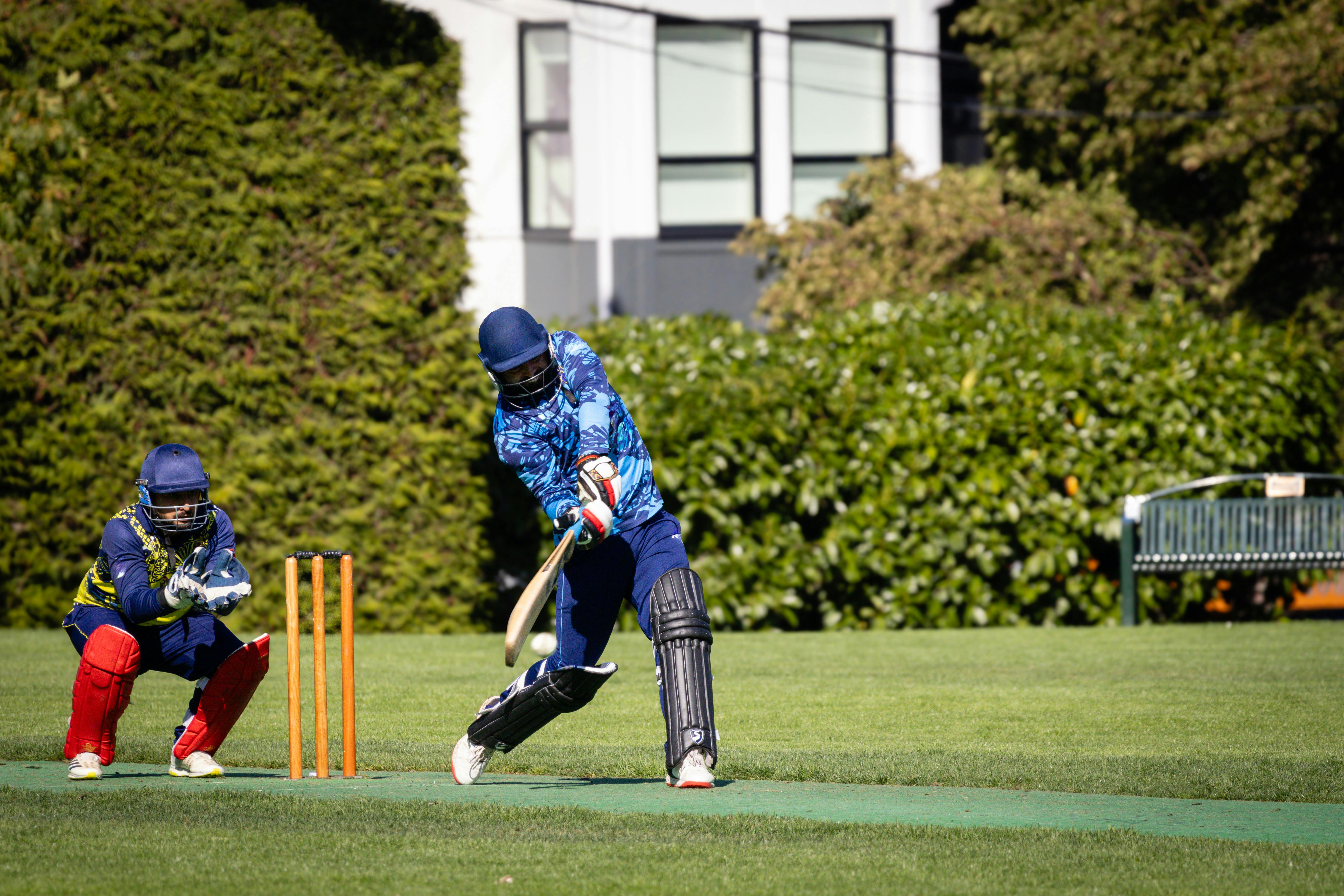 Exciting outdoor cricket match with players in full gear showcasing teamwork and sportsmanship.